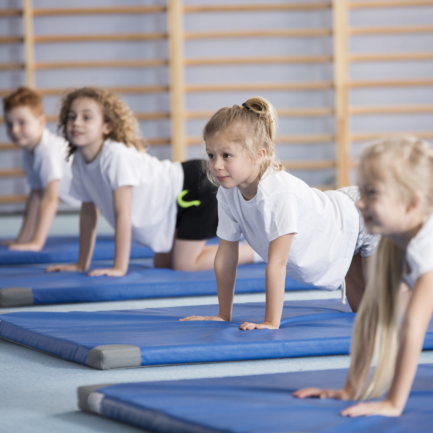 Happy girl exercising on blue mat during corrective gymnastics classes